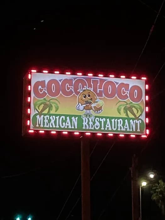 Illuminated Coco Loco roadside sign at night with coconut mascot